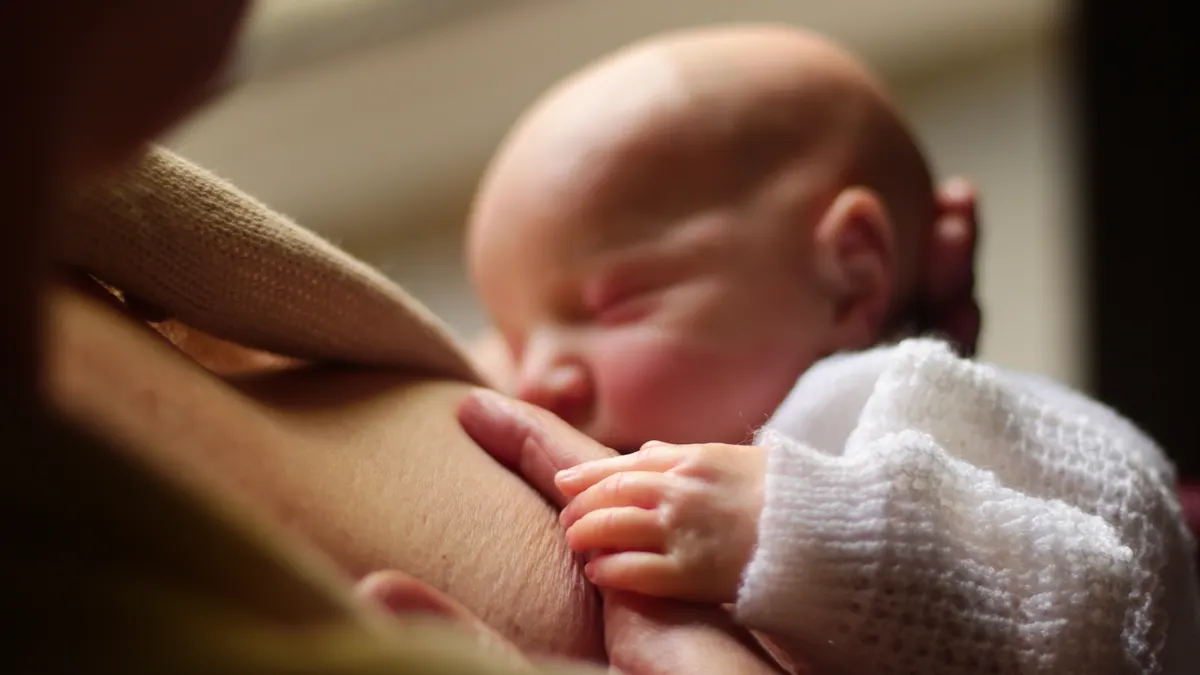 Breastfeeding latch: how to get a deeper latch step by step Baby nursing at the breast in close-up