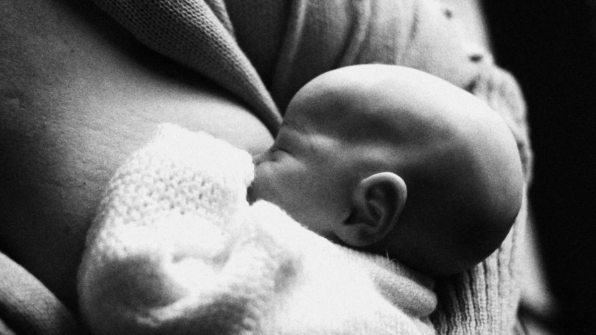 Black-and-white photo of a baby breastfeeding