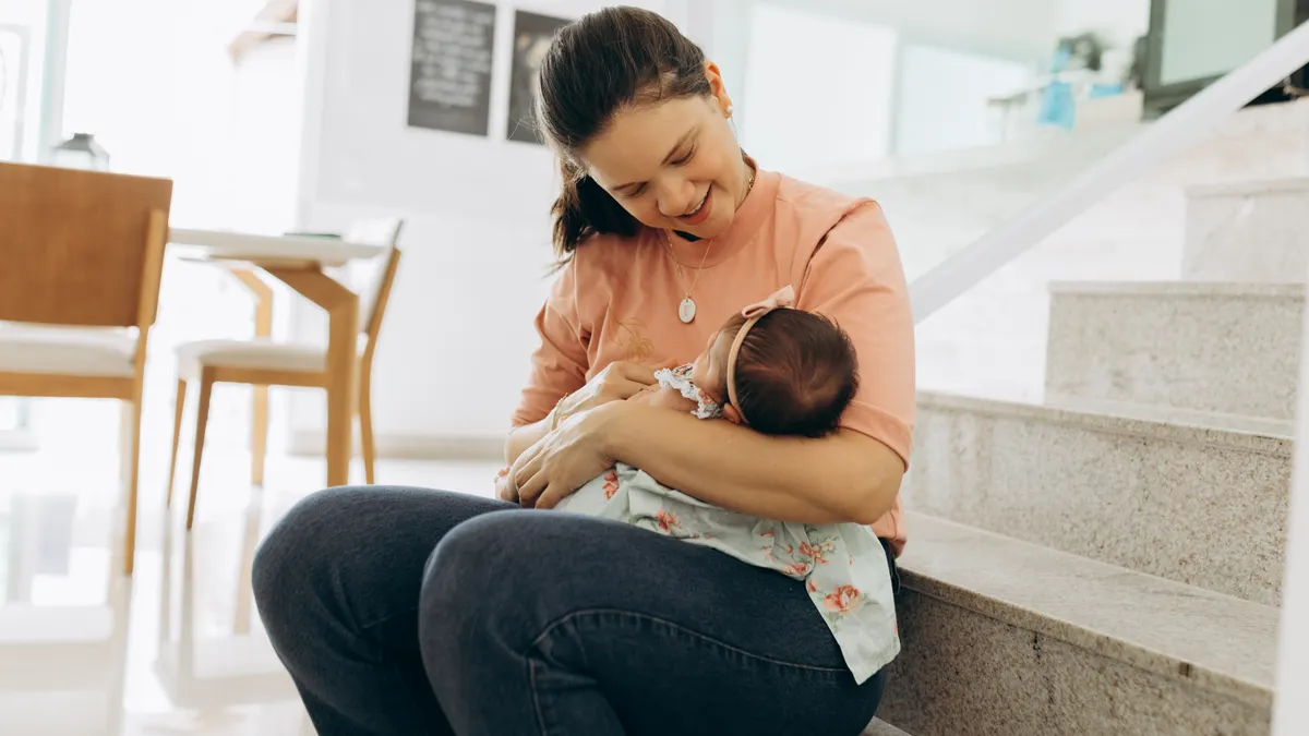 Woman seated and holding a baby in her lap