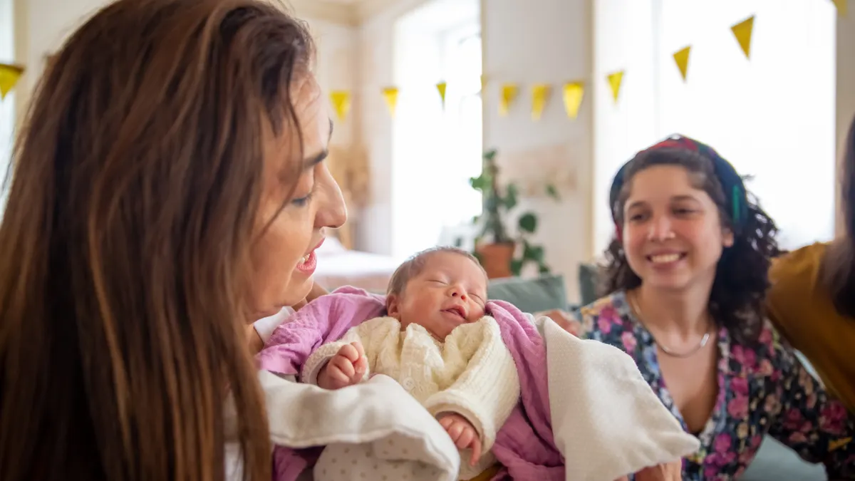 Adult holding a newborn baby indoors