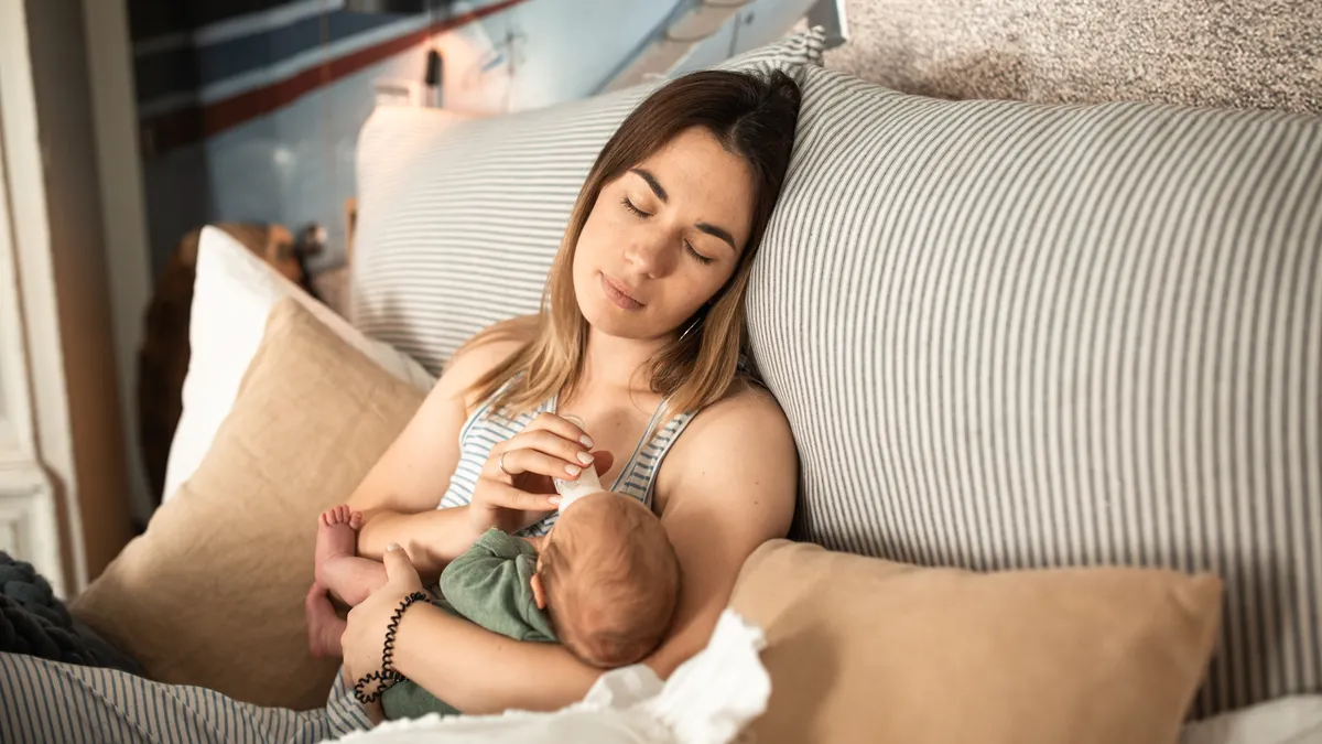 Mother reclining while breastfeeding a baby on a couch