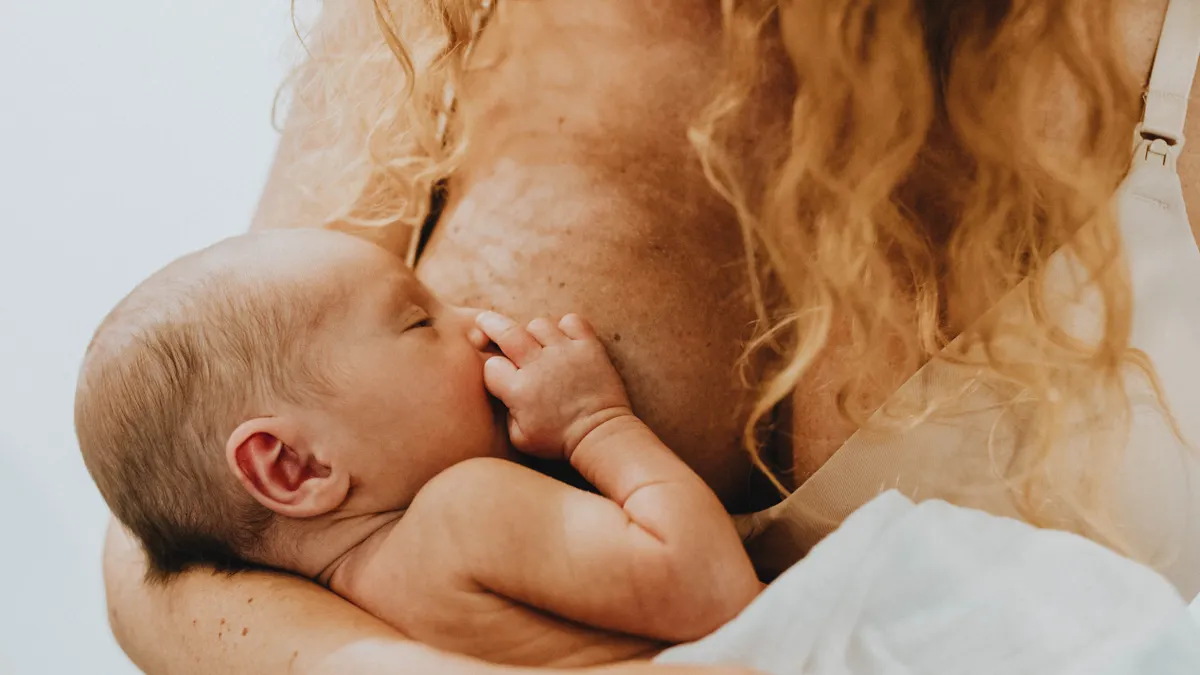 How to pump breast milk: a beginner's routine for new parents Mother breastfeeding an infant in a close-up