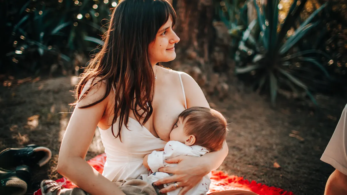 woman breastfeeding a baby outdoors on a blanket