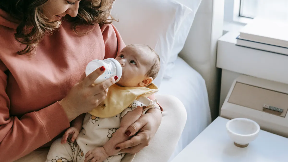 mother feeding a baby with a bottle in a bright room