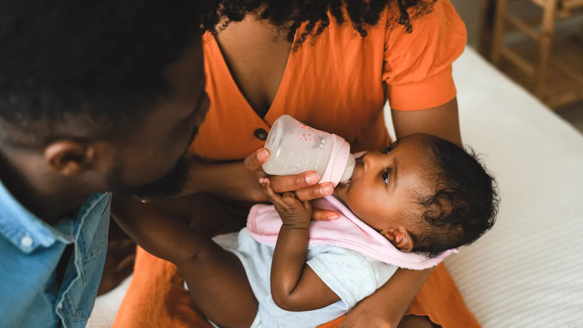 Parents bottle-feeding a baby together